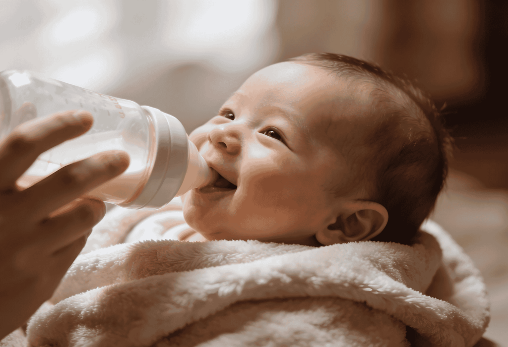 Bébé souriant buvant son biberon de lait infantile enveloppé dans une couverture douce