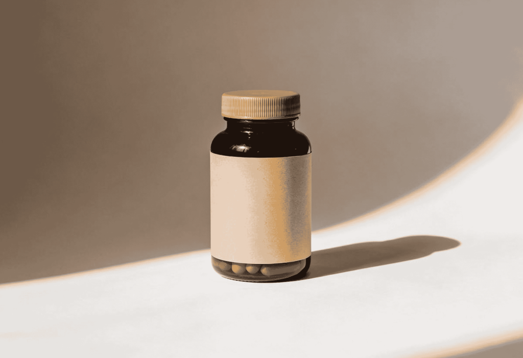 Flacon ambré de compléments alimentaires avec étiquette kraft sur fond neutre à la Pharmacie Merceron Capbreton